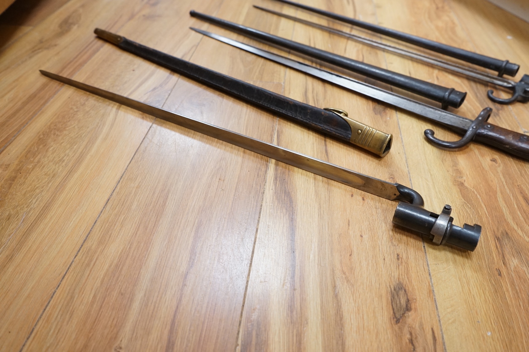 Three bayonets; a gras bayonet, a Lebel bayonet and an Indian Enfield style triangular socket bayonet, all in the original scabbards